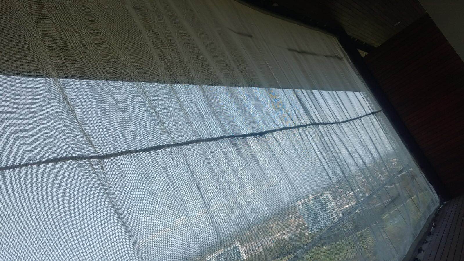 Interior view of a tall translucent AquaGrid screen with the city visible through the fabric.