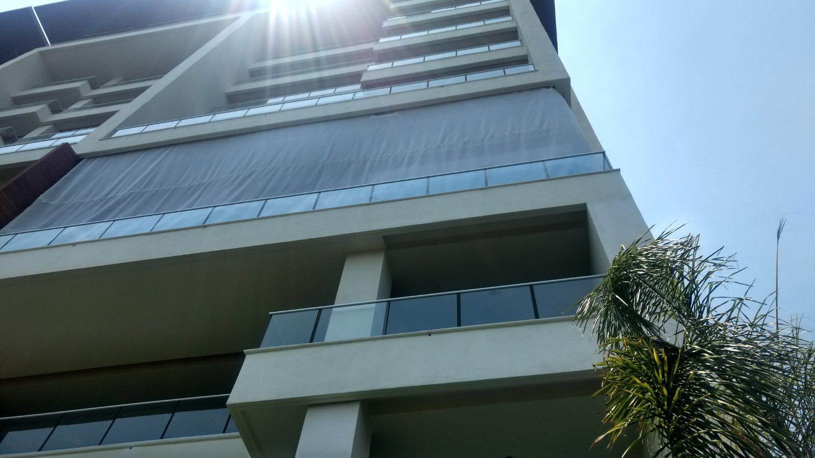 View from below of a multistory building with an AquaGrid screen between balconies.