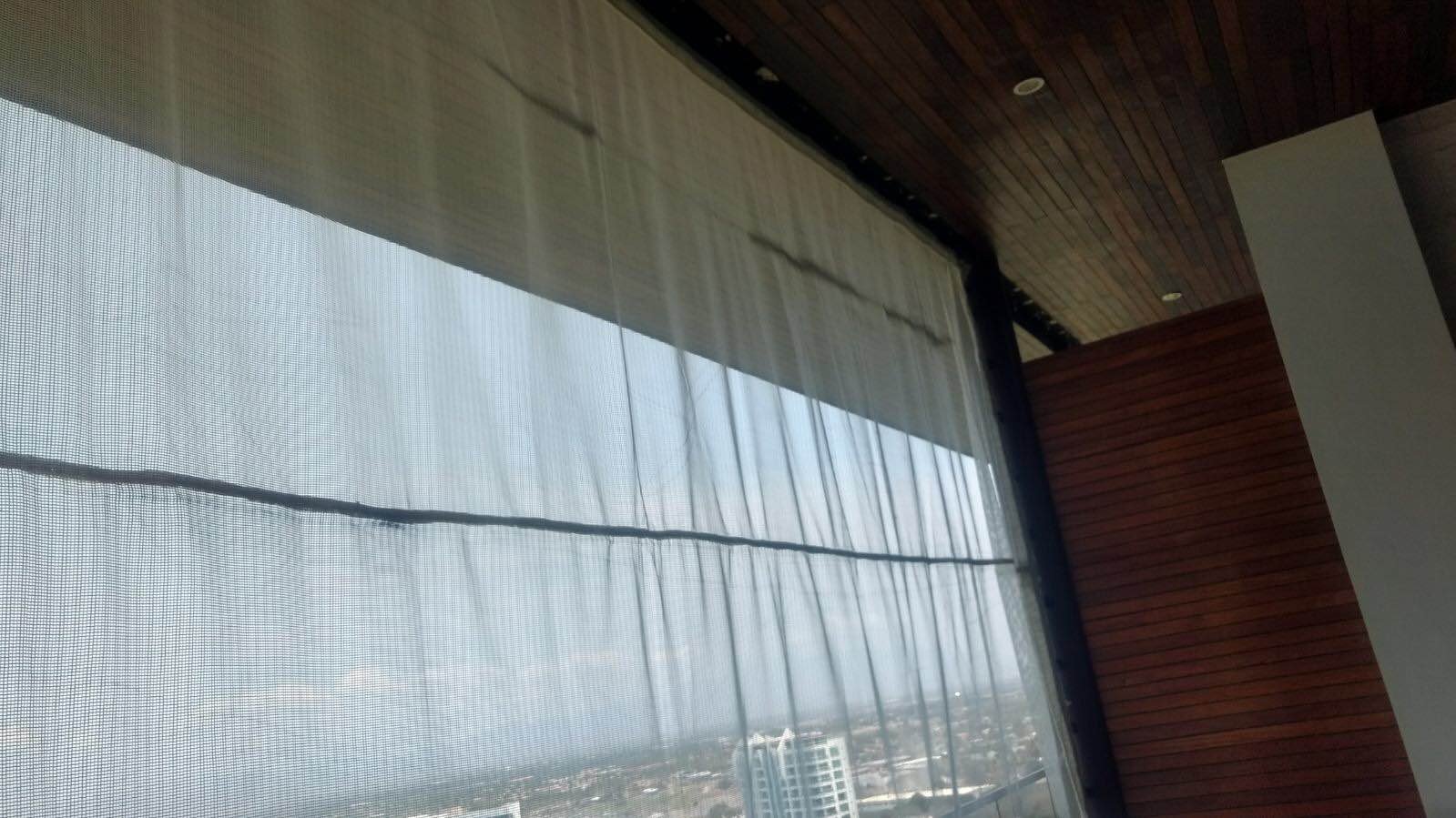 Translucent AquaGrid screen across a wide opening beneath a wooden roof, with a visible horizontal support.